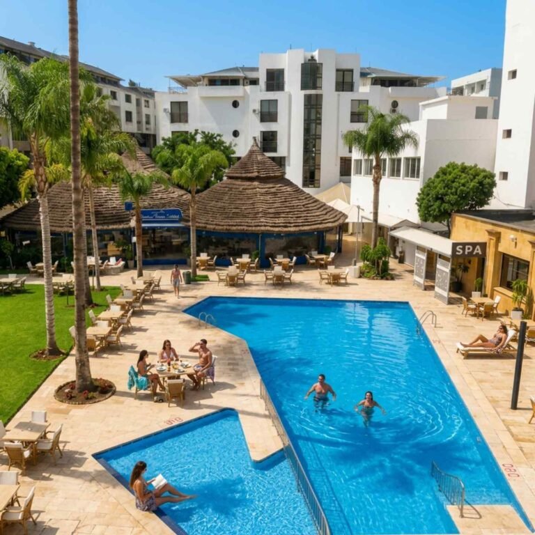 Piscine extérieure à Tanger entourée de verdure avec vue sur le restaurant Chiringuito Malibu Club de l'hôtel El Oumnia Puerto