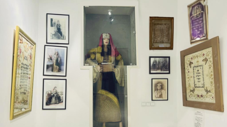 Synagogues et musées juifs de la médina de Tanger : un parcours de mémoire géré par la Communauté Israélite de Tanger Mannequin portant la robe de mariée Berberisca dans une vitrine de la synagogue Moshé Nahon, un site incontournable du réseau des synagogues et musées juifs de Tanger, entouré de photographies anciennes et de broderies traditionnelles.