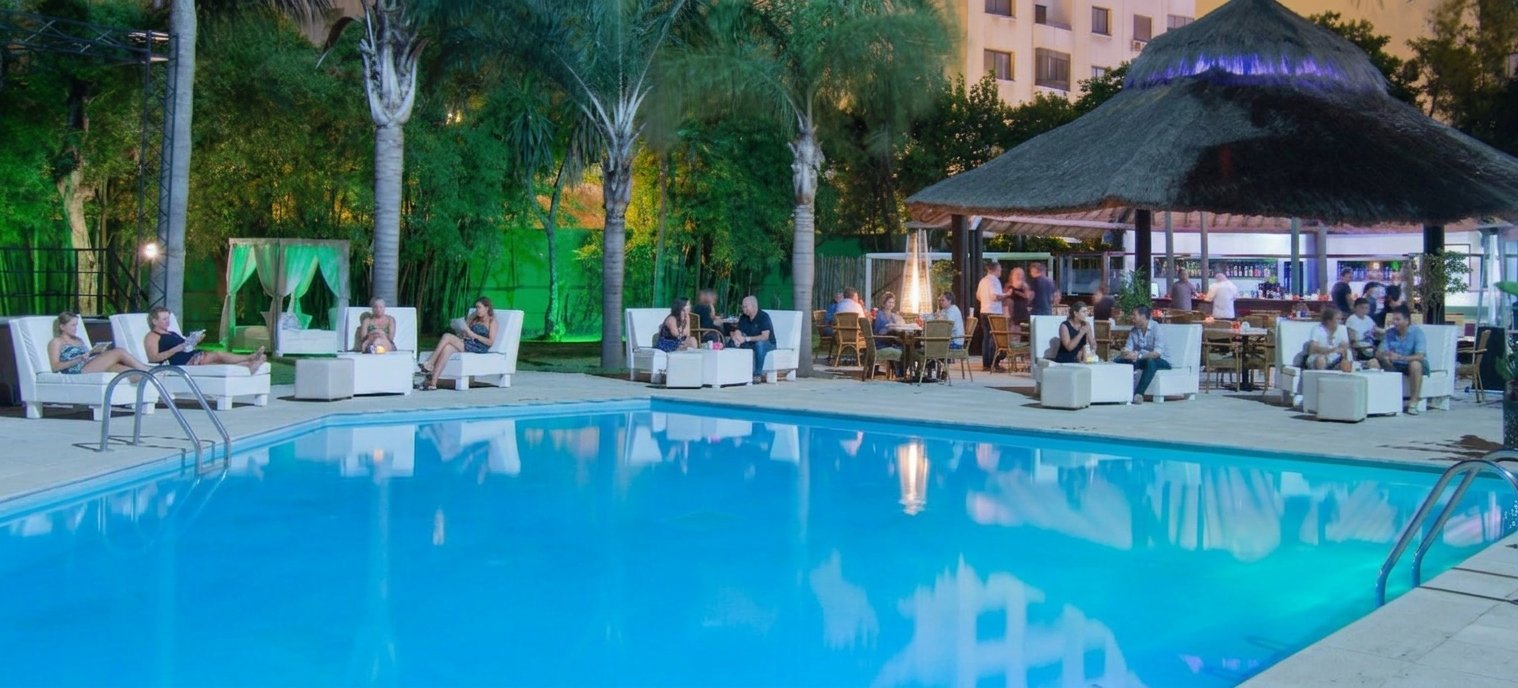 Clients installés autour de la piscine extérieure éclairée lors d'une soirée à Tanger en septembre.