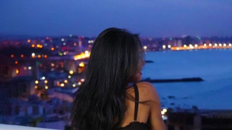 Série vacances en septembre – Hôtel Farah Tanger : Notre premier arrêt au cœur de la douceur d’arrière-saison Femme admirant la vue nocturne et le crépuscule au Farah hotel Tanger depuis les hauteurs.