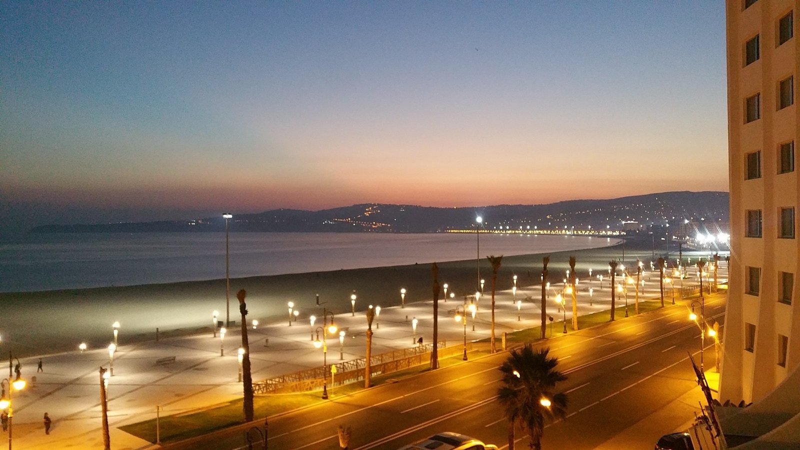 Lueurs crépusculaires et réverbères allumés sur la corniche et la plage depuis le bâtiment du Kenzi Solazur Tanger.