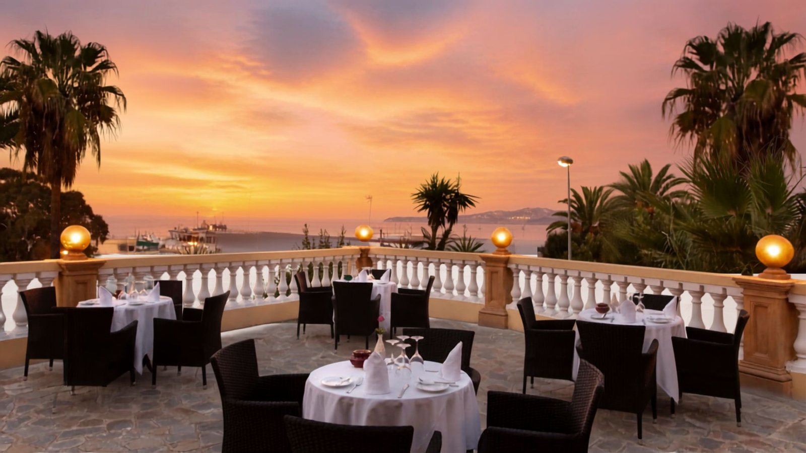 Tables de restaurant dressées sur la terrasse face à la mer lors d'un crépuscule à la Villa de France Tanger.