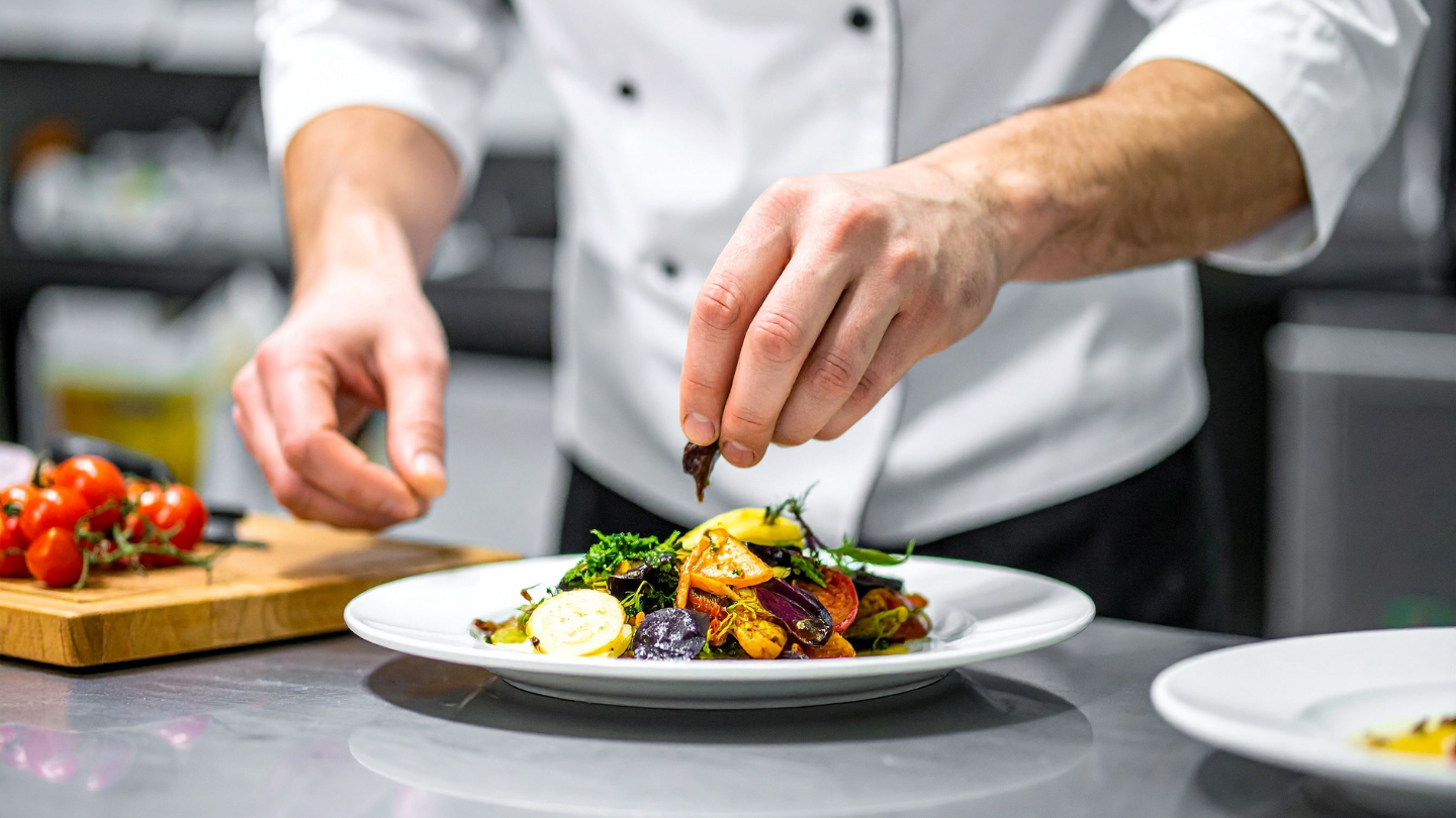 mains d'un chef cuisinier dressant avec minutie une assiette gastronomique pour illustrer la Saga culinaire de Tanger.
