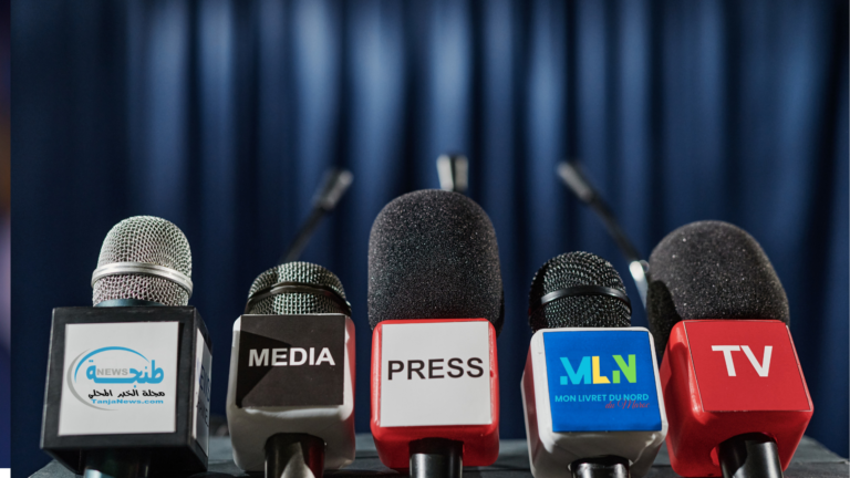 Salles de séminaires et congrès à Tanger : Le guide des espaces d’événements de prestige Une rangée de microphones de presse et de télévision, alignés pour une conférence de presse d'affaires à Tanger, arborant les logos de TanjaNews et MLN Mon Livret du Nord.