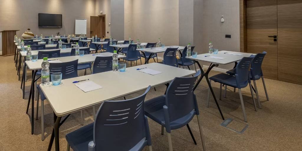 Espaces événementiels aménagés en style classe avec chaises bleues et paperboard.