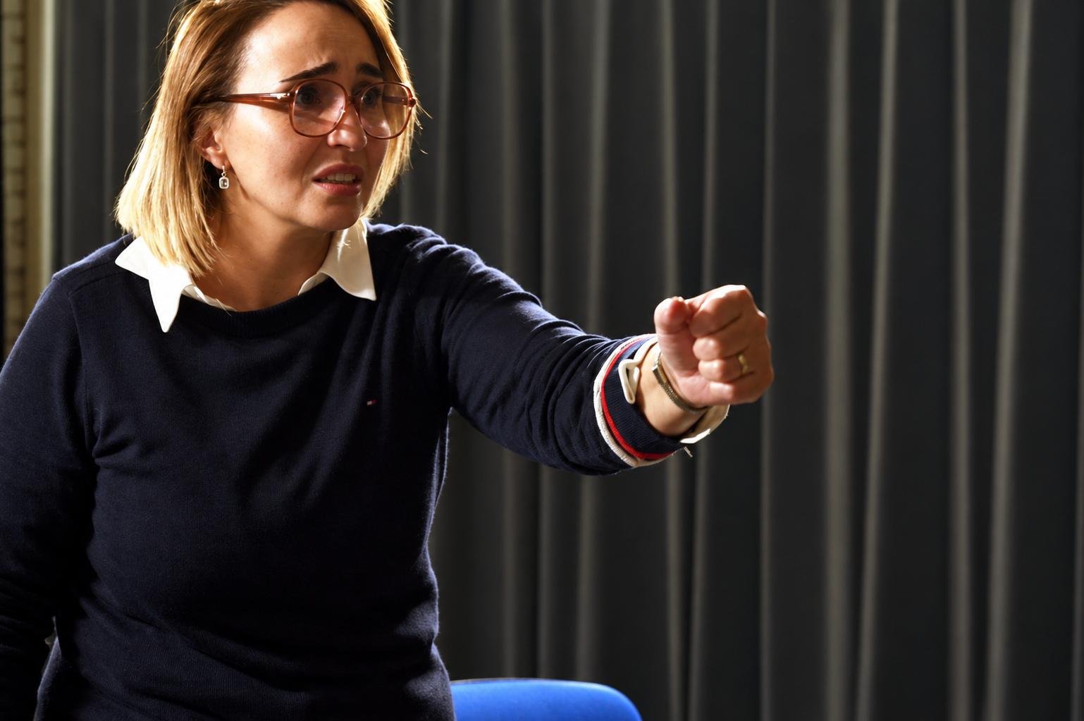 Nadia Lamarti debout sur scène exprimant une vive émotion pendant sa représentation de théâtre.