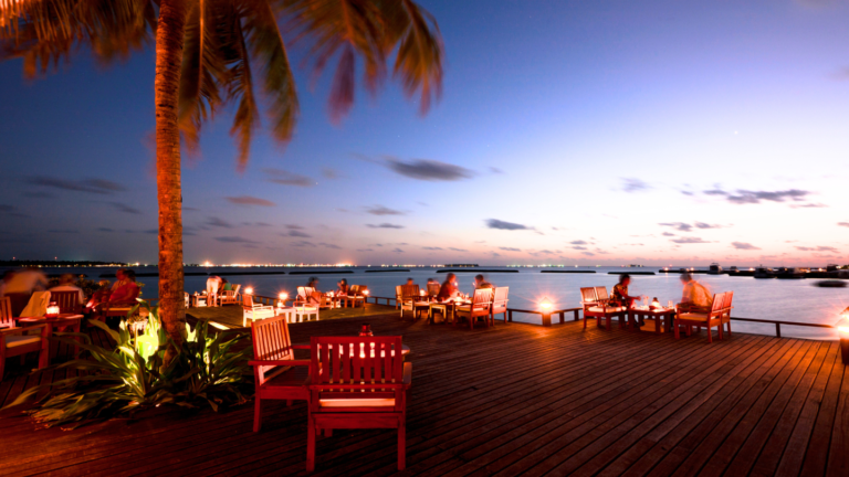 Terrasse en bois d'un restaurant en bord de mer aux lueurs nuancées du crépuscule pour le lancement de la saga culinaire de Tanger.