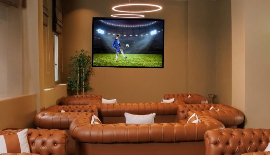 Intérieur de l'Arena Sports Bar à l'hôtel Kenzi Solazur à Tanger, avec de grands canapés en cuir marron chesterfield et des écrans diffusant un match de football.