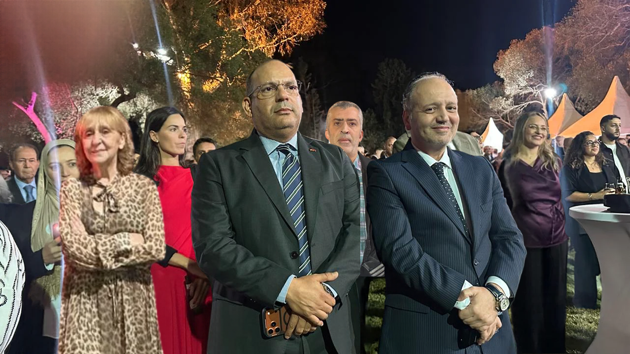 invités souriants à la fête nationale de l'Espagne, posant de nuit dans les jardins illuminés du Consulat Général à Tanger, en face du pupitre de discours.