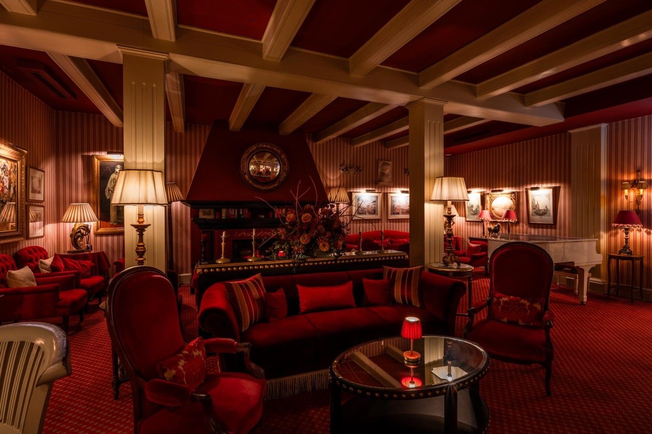 Ambiance tamisée avec salons rouges et piano blanc au bar de l'hôtel Le Mirage a Tanger.