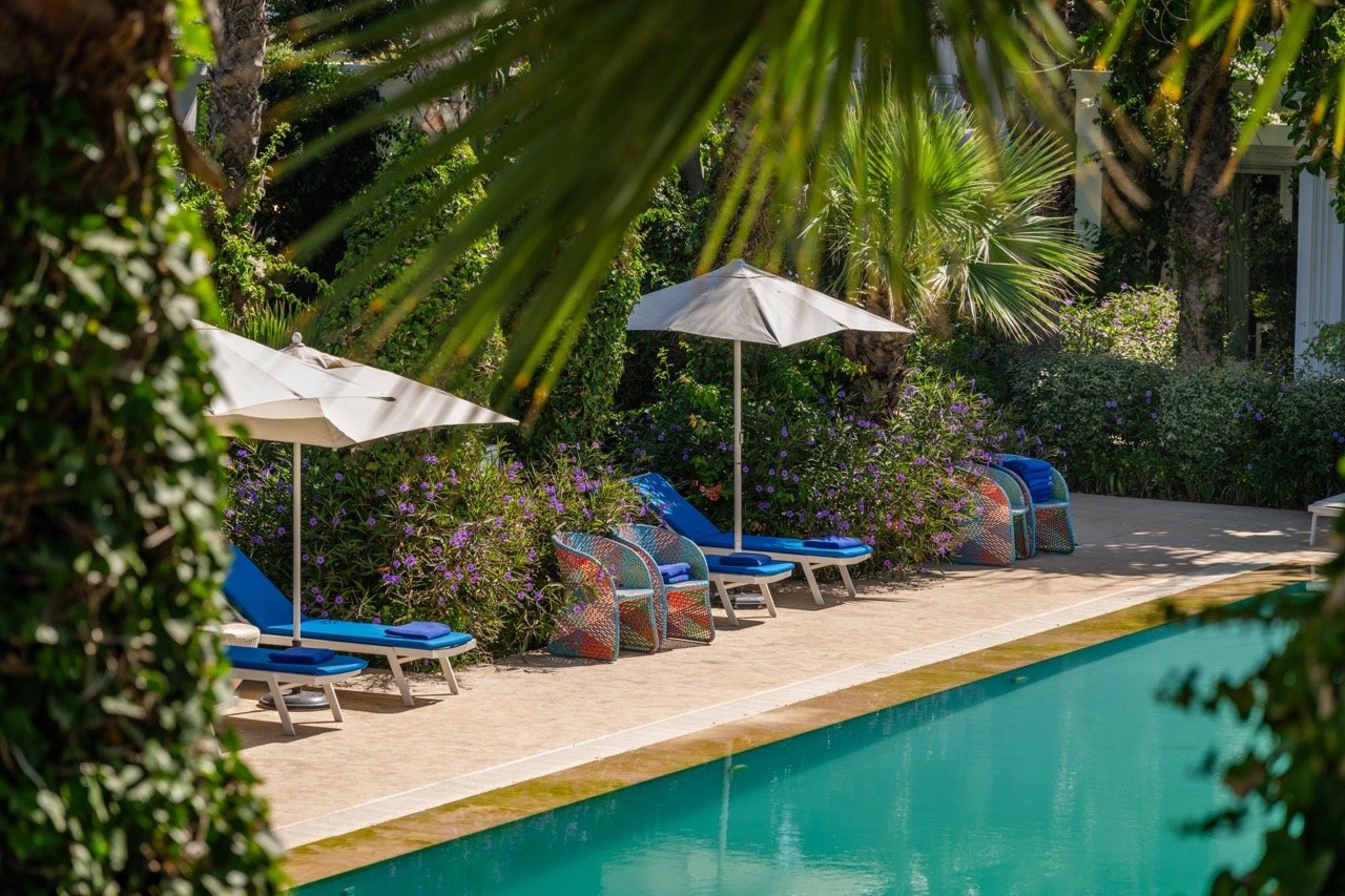 Espace piscine arboré et transats du Pool Bar de l'hôtel Le Mirage à Tanger.