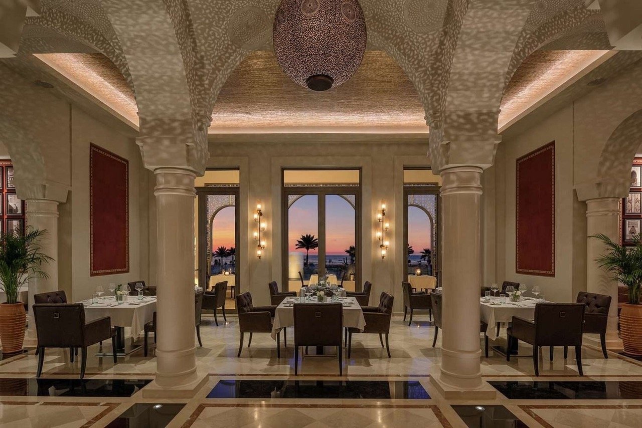 Tables de restaurant élégantes sous des arcades traditionnelles ciselées aux restaurants du Hilton Al Houara à Tanger.