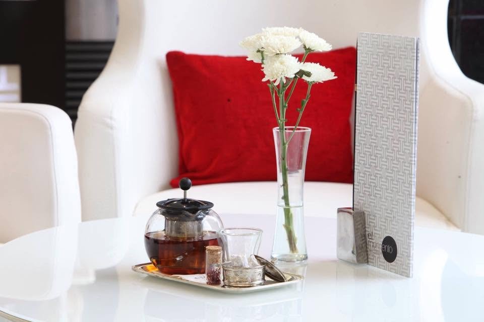 Une théière en verre infusant sur une table blanche à côté du menu officiel de l'espace El Momento.