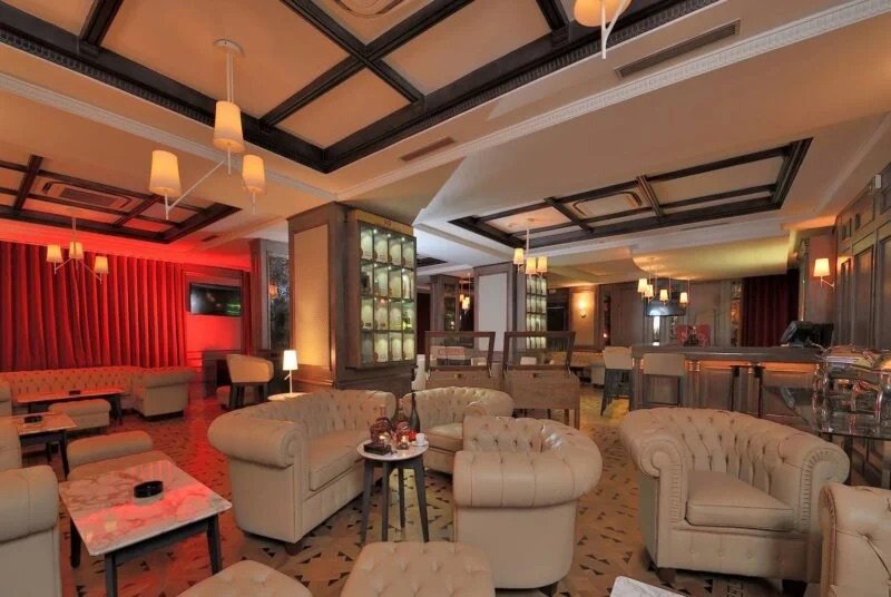 Fauteuils Chesterfield en cuir et boiseries brutes dans le décor raffiné du XO Luxury Bar Cognac & Cigar Club, un espace exclusif des restaurants du Royal Tulip.